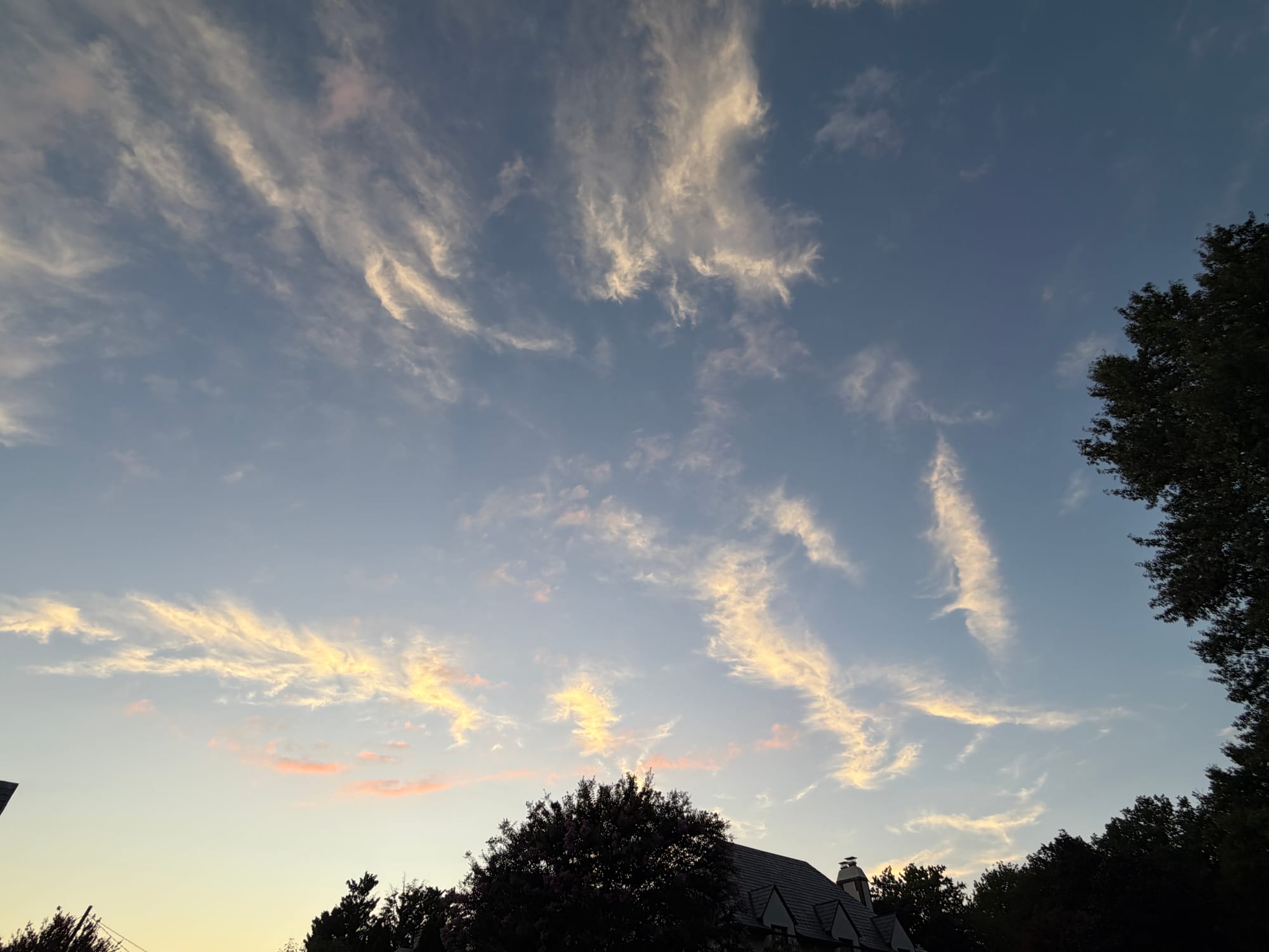 Whispy white clouds against a dusky sky at sunset