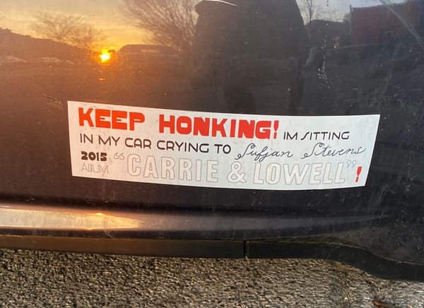 Bumper Sticker reads: "Keep Honking! I'm sitting in my car crying to Sufjan Stevens 2015 album Carrie & Lowell"