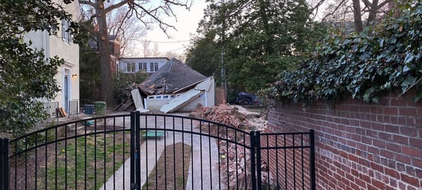 In a wealthy neighborhood, a crushed garage & ruins a of a brick wall