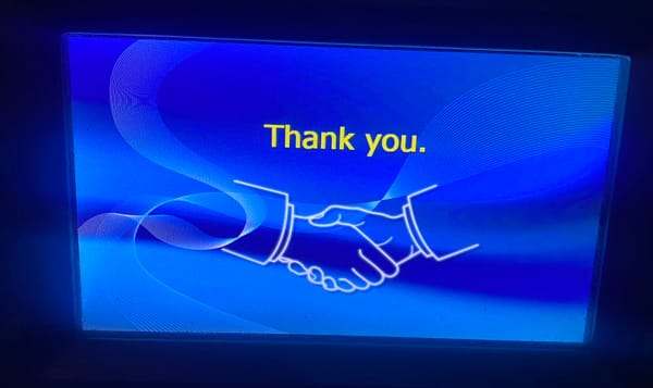 Blue ATM screen. Yellow "Thank You." text sits above a white line drawing of two hands embraced in a business-like shake