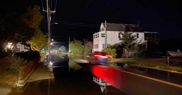 A car drives thru flooded waters at night